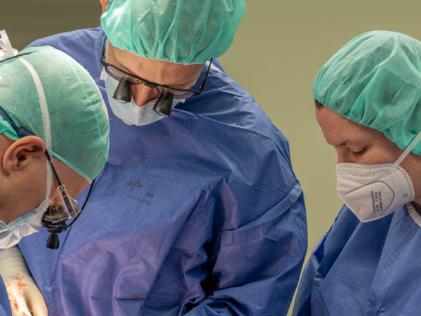 Drei medizinische Fachkräfte über dem OP-Tisch gebeugt, Team, Deutsches Diakonisches Herz- und Gefäßzentrum, Berlin, Hamburg