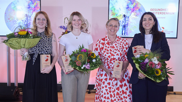 Die Gewinnerinnen stehen auf der Bühne nebeneinander mit Blumensträußen Die Gewinnerinnen stehen auf der Bühne nebeneinander mit Blumensträußen