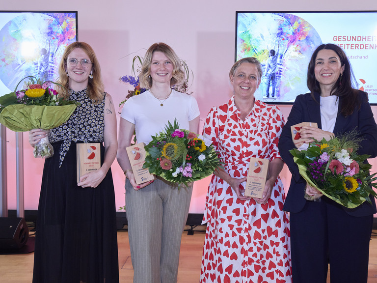 Die Gewinnerinnen stehen auf der Bühne nebeneinander mit Blumensträußen